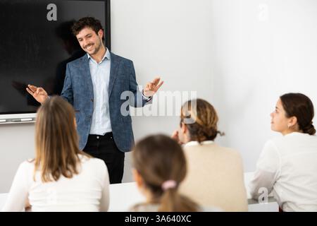 Young male teacher giving lecture to group of student Stock Photo