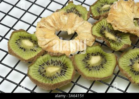 Dried pineapple slices and dried kiwi slices on a wire rack Stock Photo