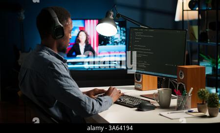 African american male programmer working on cloud computing with an algorithm, writing code for optimization on terminal window. IT specialist inserts html code, server security. Camera B. Stock Photo