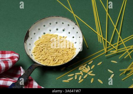 Semi di orzo in sieve ladle, pasta variety in the form of cereal grains and spaghetti Stock Photo
