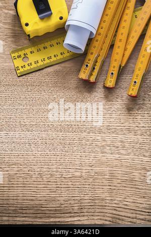 Construction plans and yellow instruments of measurement on oaken wooden board maintenance concept Stock Photo