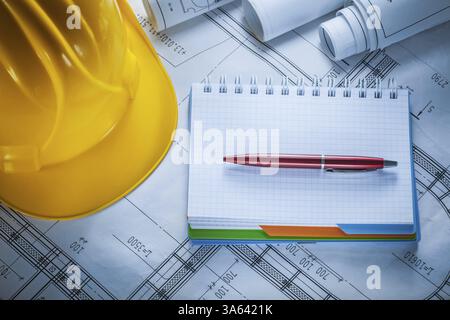 Hard hat checked notebook pen blueprints on construction drawing Stock Photo