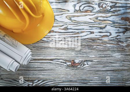 Rolled construction plans building helmet on vintage wooden board Stock Photo