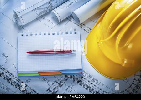 Safety building helmet checked notebook pen blueprints on construction plan Stock Photo