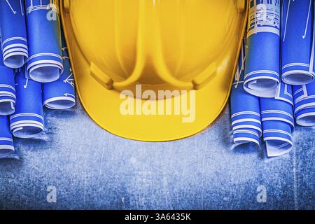 Blue rolled engineering drawings yellow building helmet on metallic background construction concept Stock Photo
