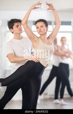 Happy contemporary ballet dancers couple dressed in black and white performing graceful choreography in hall with ballet bar Stock Photo