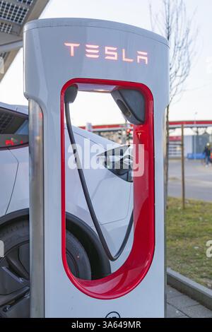 Tesla charging station, car in the background, urban environment with blue facades, Tesla, New Model Y Juniper, Germany, Europe Stock Photo