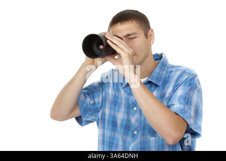 Handsome young man holding camera lens like it was spyglass on white background Stock Photo