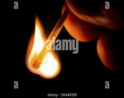 Fire from match in darkness. Hand holding match Stock Photo
