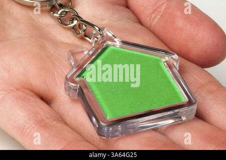 Keychain with figure of green house. Hand holding key and Keychain Stock Photo