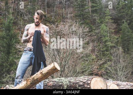 Young men on logs in the forest. Men dress Stock Photo