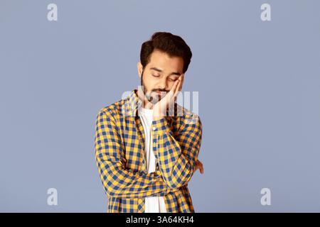 Tired Indian guy sleeping after overworking on lilac background Stock Photo