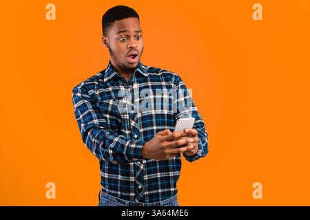 African Man Holding Cellphone Reading Wow News On Yellow Background Stock Photo