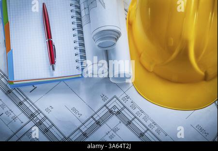 Protective building helmet checked notebook pen blueprints on construction plan Stock Photo