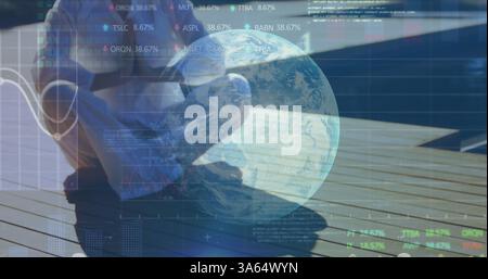 Person sitting on deck using laptop, analyzing global financial data trends Stock Photo