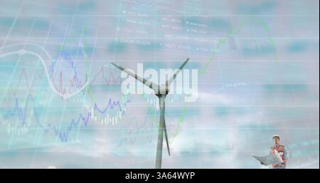 Engineer analyzing wind turbine data with charts overlaying sky background Stock Photo