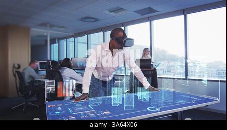 In modern office, man using VR headset interacting with futuristic digital table Stock Photo