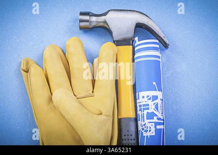 Claw hammer protective gloves rolled up construction drawings on blue ...