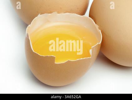 Tree whole eggs and another broken in half raw egg and yolk inside. Placed on white background Stock Photo