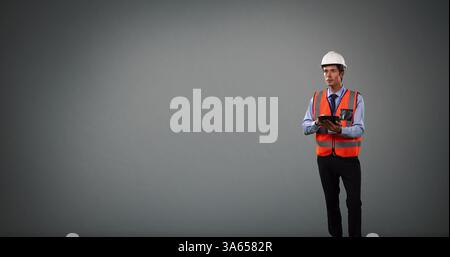 Construction engineer in hard hat and safety vest using tablet, focused on project Stock Photo