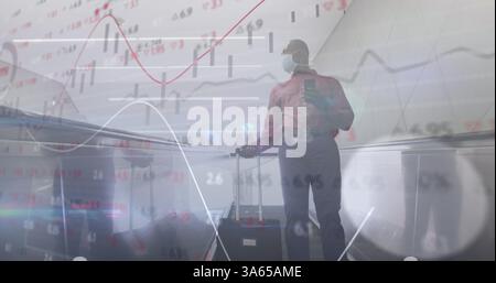 Financial data processing against man wearing face mask with trolley bag using smartphone Stock Photo