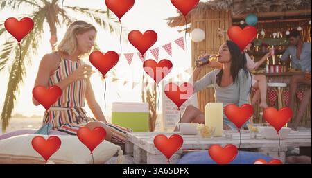 Image of red heart love balloons digital icons over friends having drinks in beach bar Stock Photo