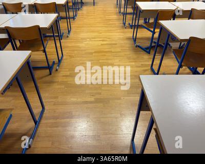 Empty Classroom with Wooden Floor and Student Desks Stock Photo