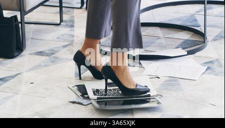 Angry, feet and business woman on laptop in office frustrated for network crisis, glitch and mistake. Professional, corporate and person crush, break Stock Photo
