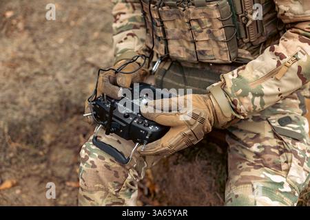 A soldier remotely controls a drone. Control panel in military hands. Stock Photo