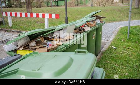Row of brimful municipal paper bank waste trash cans with open lids for cardboard standing on open street in residential urban area Stock Photo