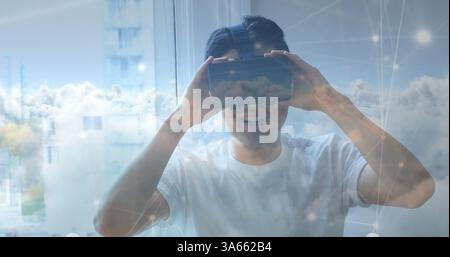 Asian man using VR headset at home, experiencing virtual reality with joy Stock Photo