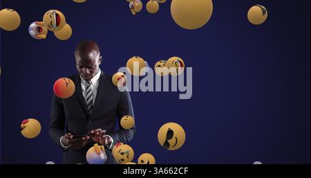 Using smartphone, businessman in suit focused on screen with floating emojis Stock Photo