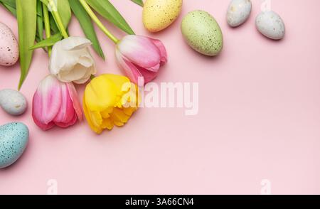 Easter eggs and tulips arranged on a pink background creating a vibrant spring border with copy space Stock Photo