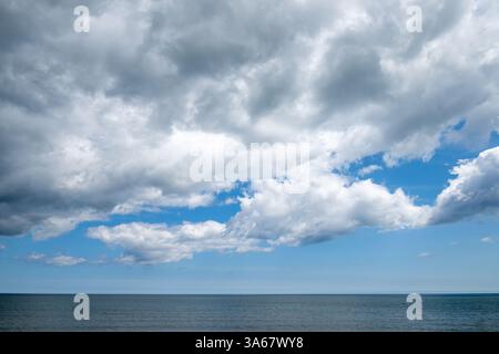 Blue sky with dramatic clouds dominates the scene, while the sea meets the distant horizon below. Stock Photo