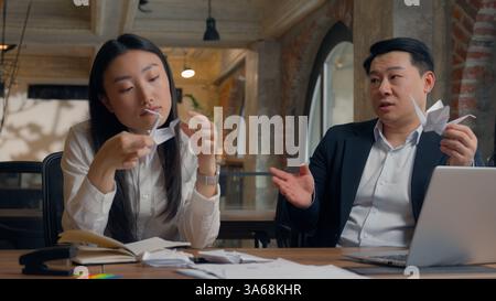 Two business colleagues coworkers Asian woman Korean businesswoman female girl Chinese man Japanese businessman guy male at office boring lazy playing Stock Photo