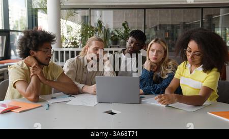 Multiracial students multiethnic five classmates African American men guys male Caucasian female women girls together studying laptop at school Stock Photo