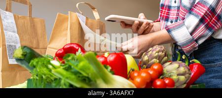 Fresh vegetables on blurred background of person scanning QR code of cash receipt Stock Photo