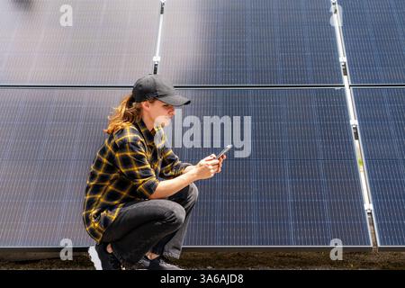 Woman monitoring PV system using her smart phone and mobile app Stock Photo