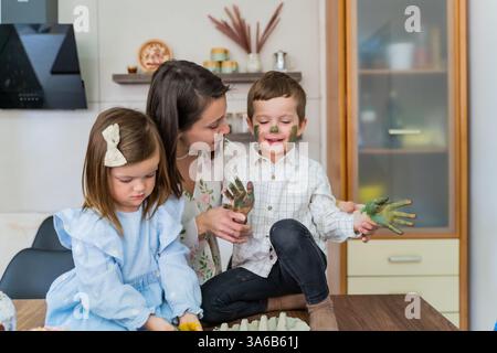Mom and children in the kitchen have fun before Easter. Easter Eve, spring Stock Photo