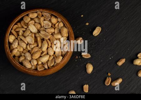peanut kernels in a wooden bowl, fried yellow peanuts with a little salt on the table Stock Photo