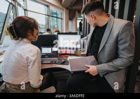 Two business professionals engage in a collaborative discussion at a modern office workspace. Stock Photo