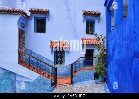 Beautiful house facade of different shades of blue with orange steps and tiled window awning, Chefchaouen, Morocco Stock Photo