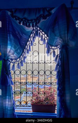 Curtains framed rainy window view through bars of Grand Mosque of Chefchaouen and Kasbah in old town medina, Chefchaouen, Morocco Stock Photo