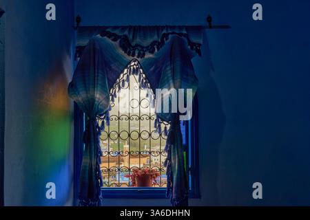 Diffused colors light through curtains framed open arched wooden window with a view of Grand Mosque of Chefchaouen and medina, Chefchaouen, Morocco Stock Photo