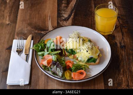 Breakfast plate with eggs benedict and glass of orange juice on rustic wooden table Stock Photo