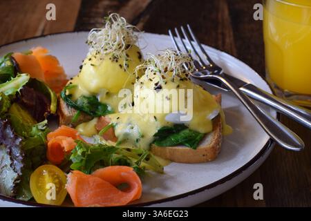 Closeup breakfast plate with eggs benedict, smoked salmon and fresh greens salad Stock Photo