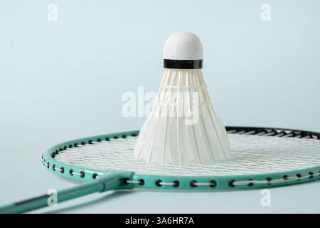 White badminton shuttlecock and badminton racket on blue background. Close up. Concept racket sport. Leisure games. Stock Photo