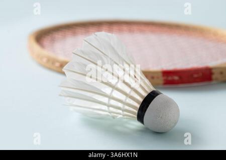 Wooden badminton rackets and white feather badminton shuttlecocks on blue background. Close up. Stock Photo