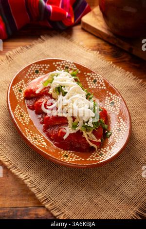 Entomatadas. Also known as Enjitomatadas, a typical dish of Mexican cuisine prepared with corn tortilla, tomato sauce and stuffed with shredded chicke Stock Photo