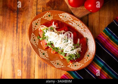 Entomatadas. Also known as Enjitomatadas, a typical dish of Mexican cuisine prepared with corn tortilla, tomato sauce and stuffed with shredded chicke Stock Photo